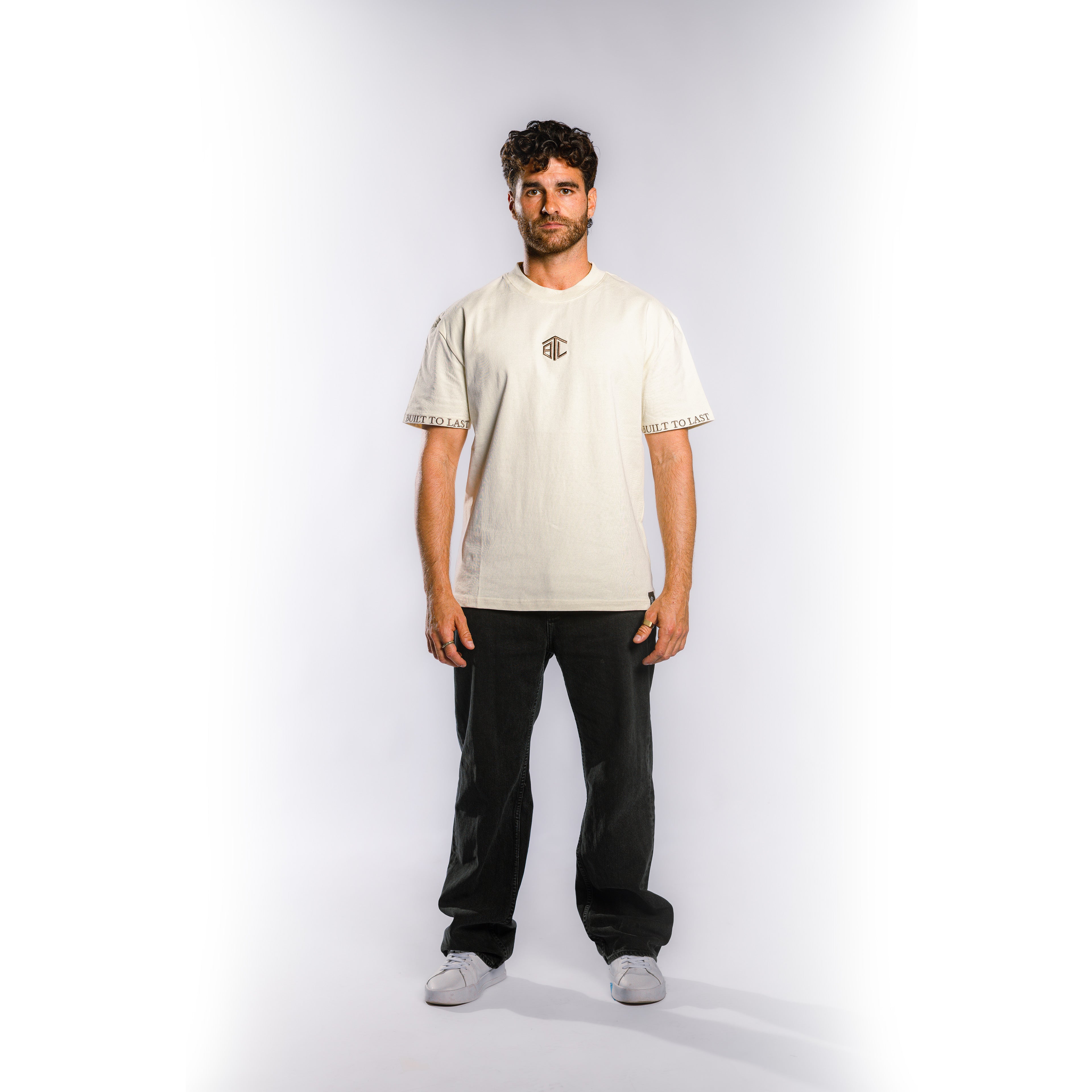Front view of model wearing Built to Last Monolith Tee White heavyweight cotton T-shirt with embroidered chest logo and branded sleeve detail