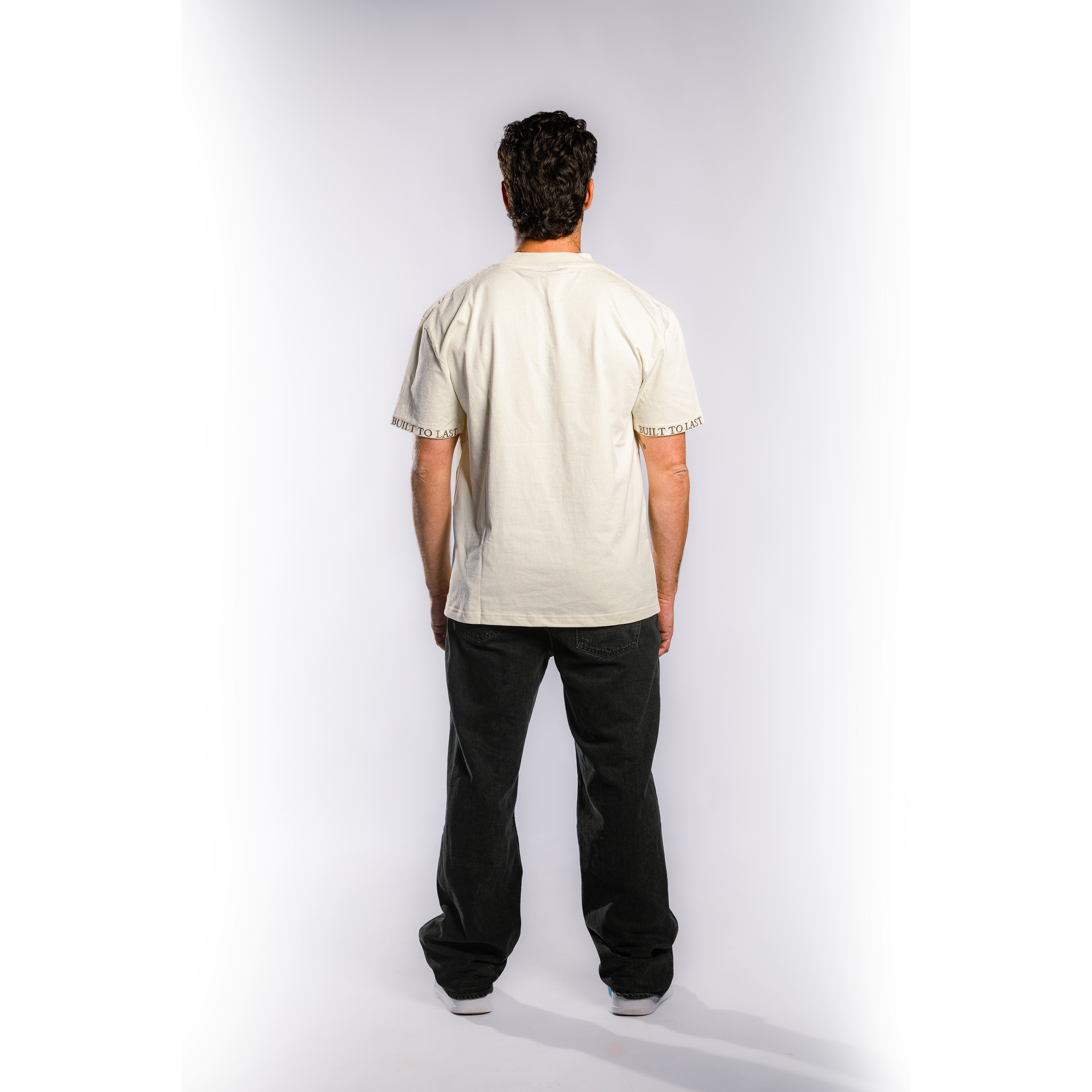 Back view of model wearing Built to Last Monolith Tee White heavyweight cotton T-shirt with branded sleeve detail
