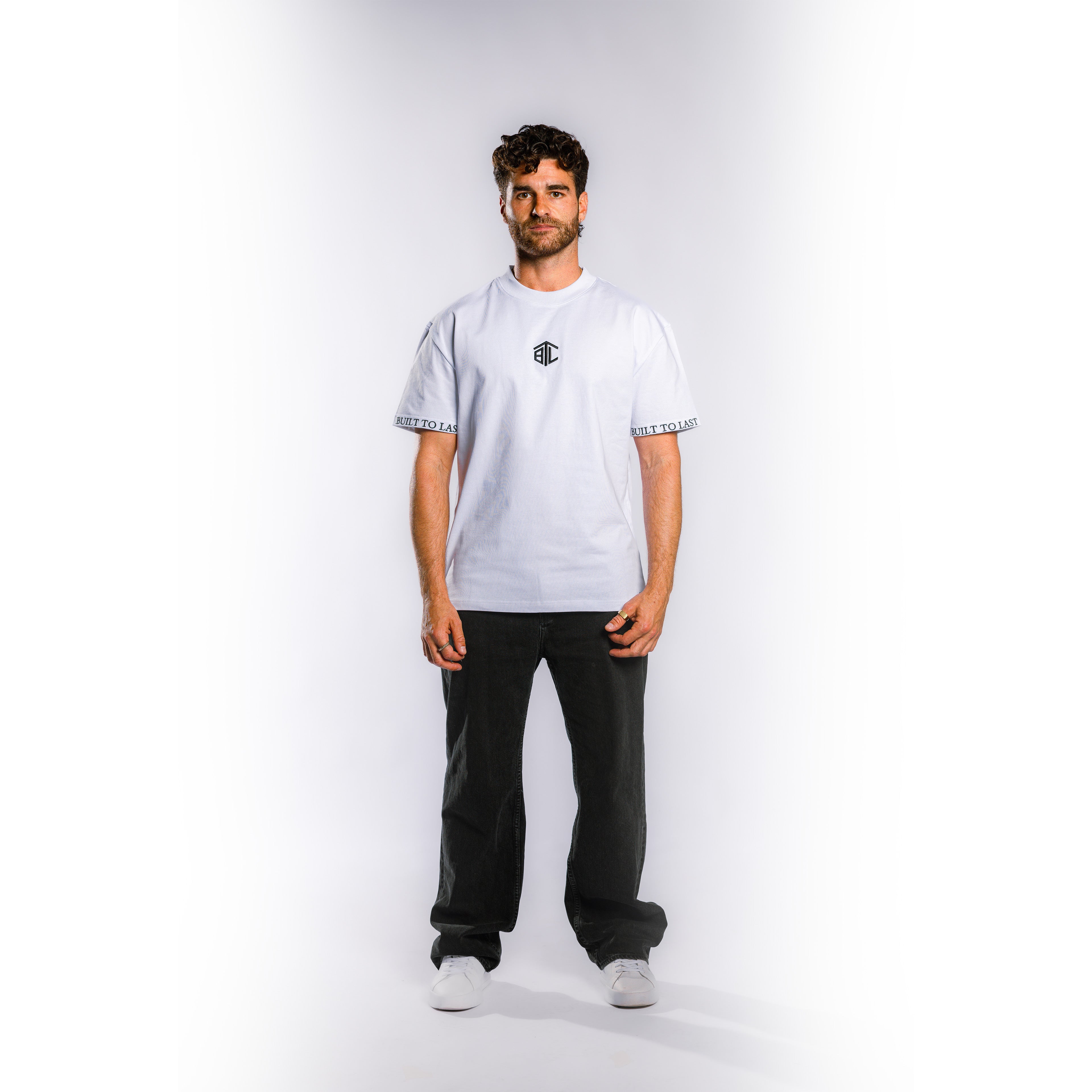 Front view of model wearing Built to Last Monolith Tee White heavyweight cotton T-shirt with embroidered chest logo and branded sleeve detail