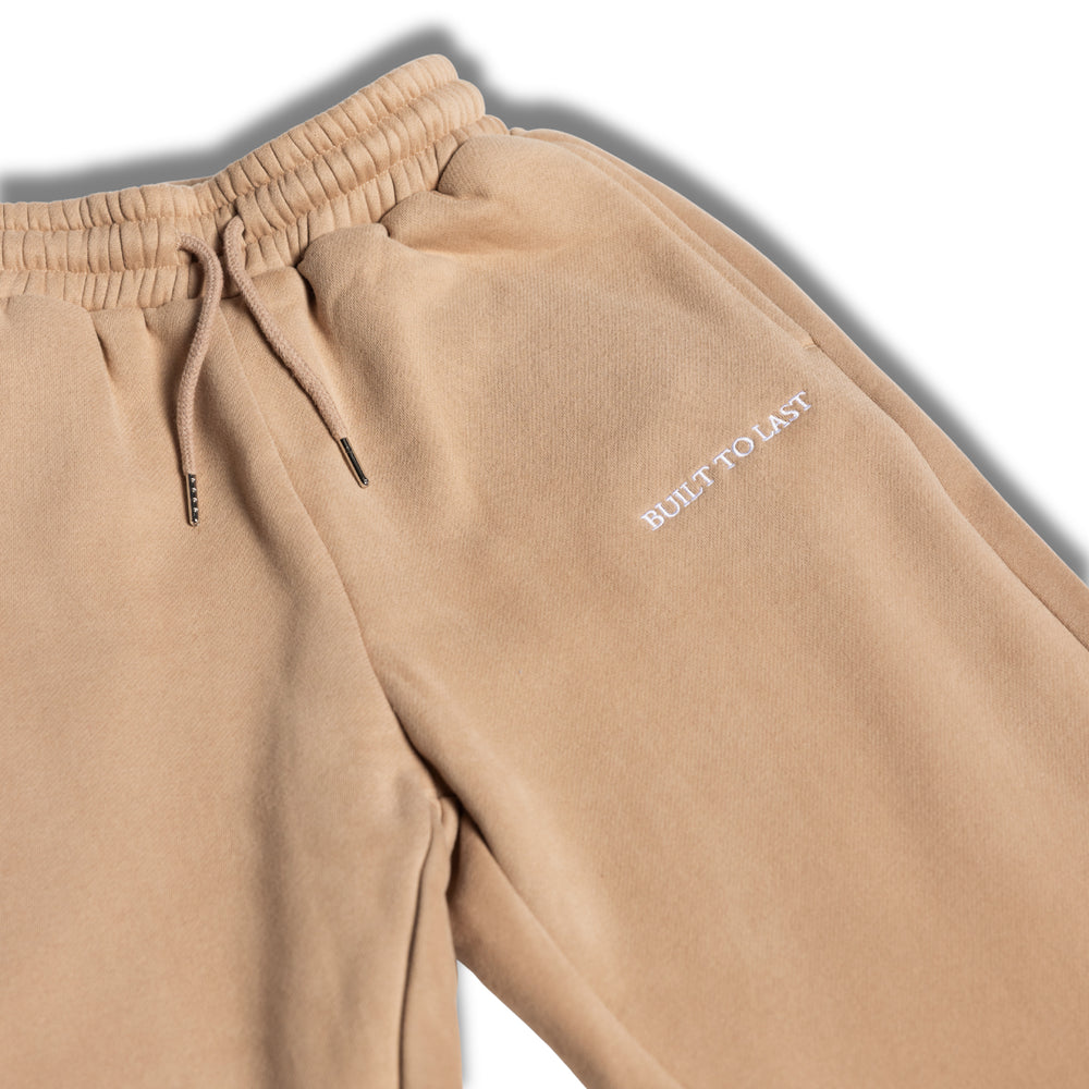 Close-up detail of waistband and logo on beige sweatpants by Built To Last.