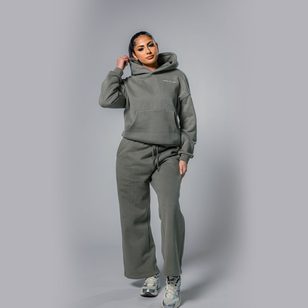Model adjusting hood of women's olive relaxed fit tracksuit set by Built To Last.