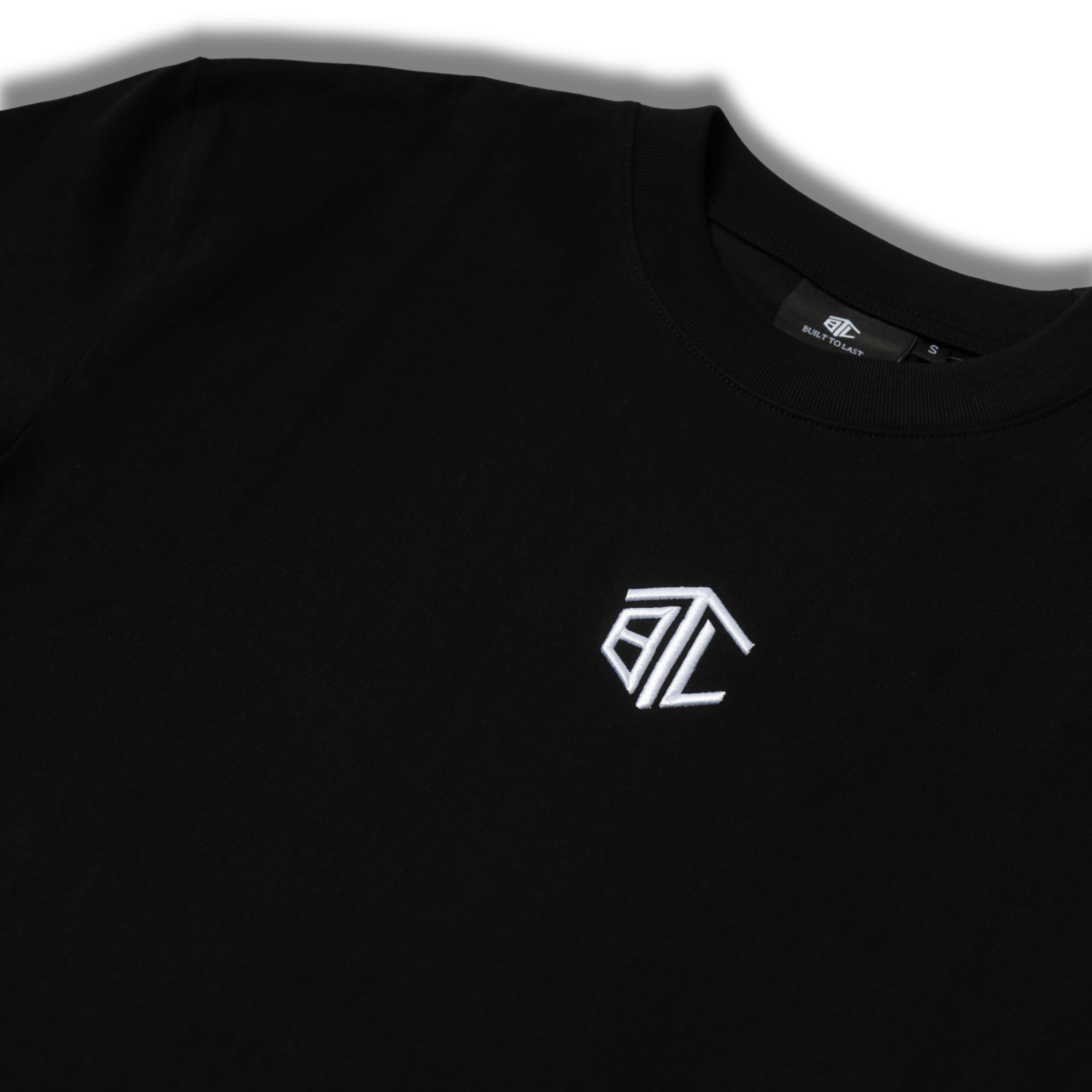 Close-up of Built to Last Monolith Tee Black embroidered chest logo on premium heavyweight cotton T-shirt