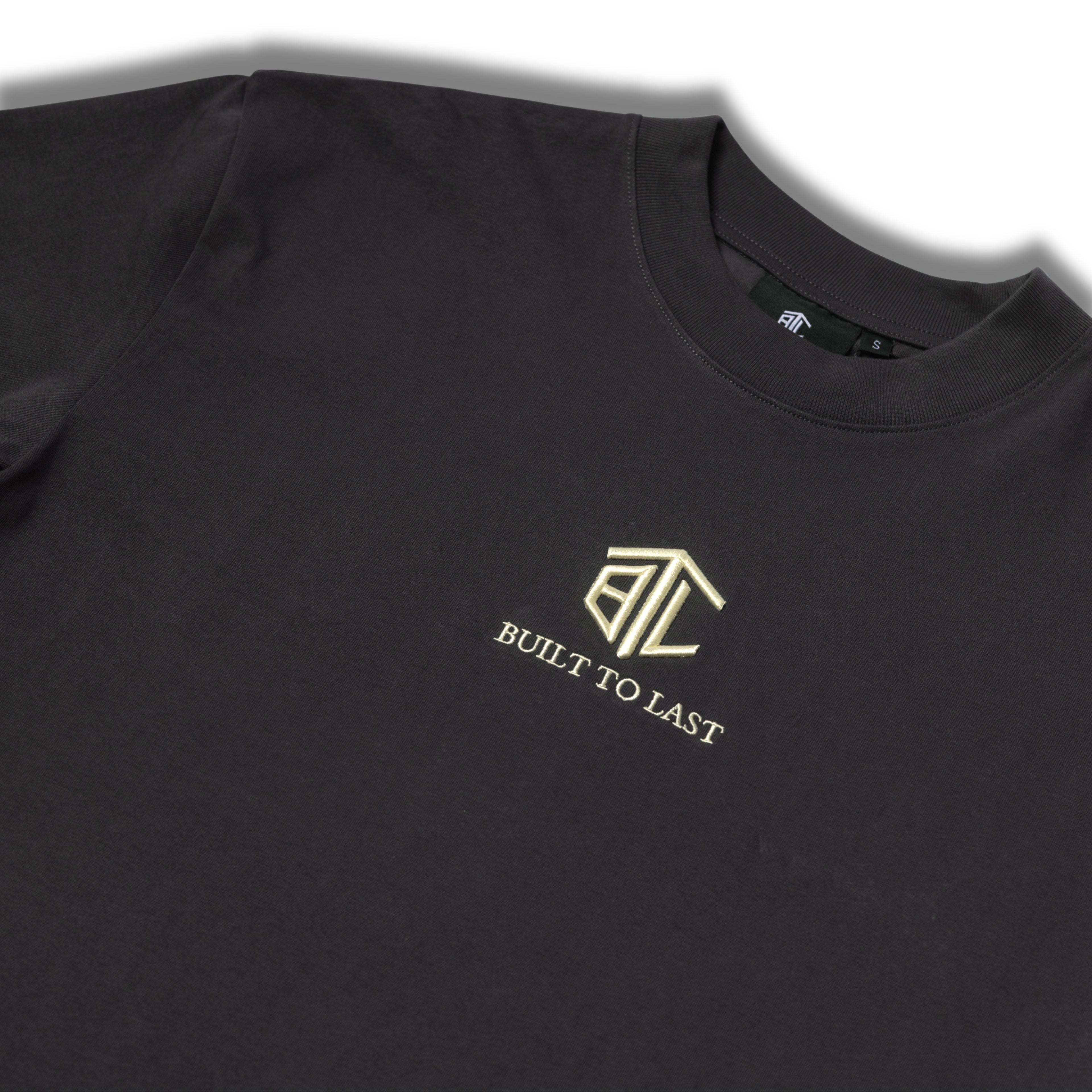 Close-up of Built to Last Eternal Tee Granite embroidered chest logo on premium heavyweight cotton T-shirt