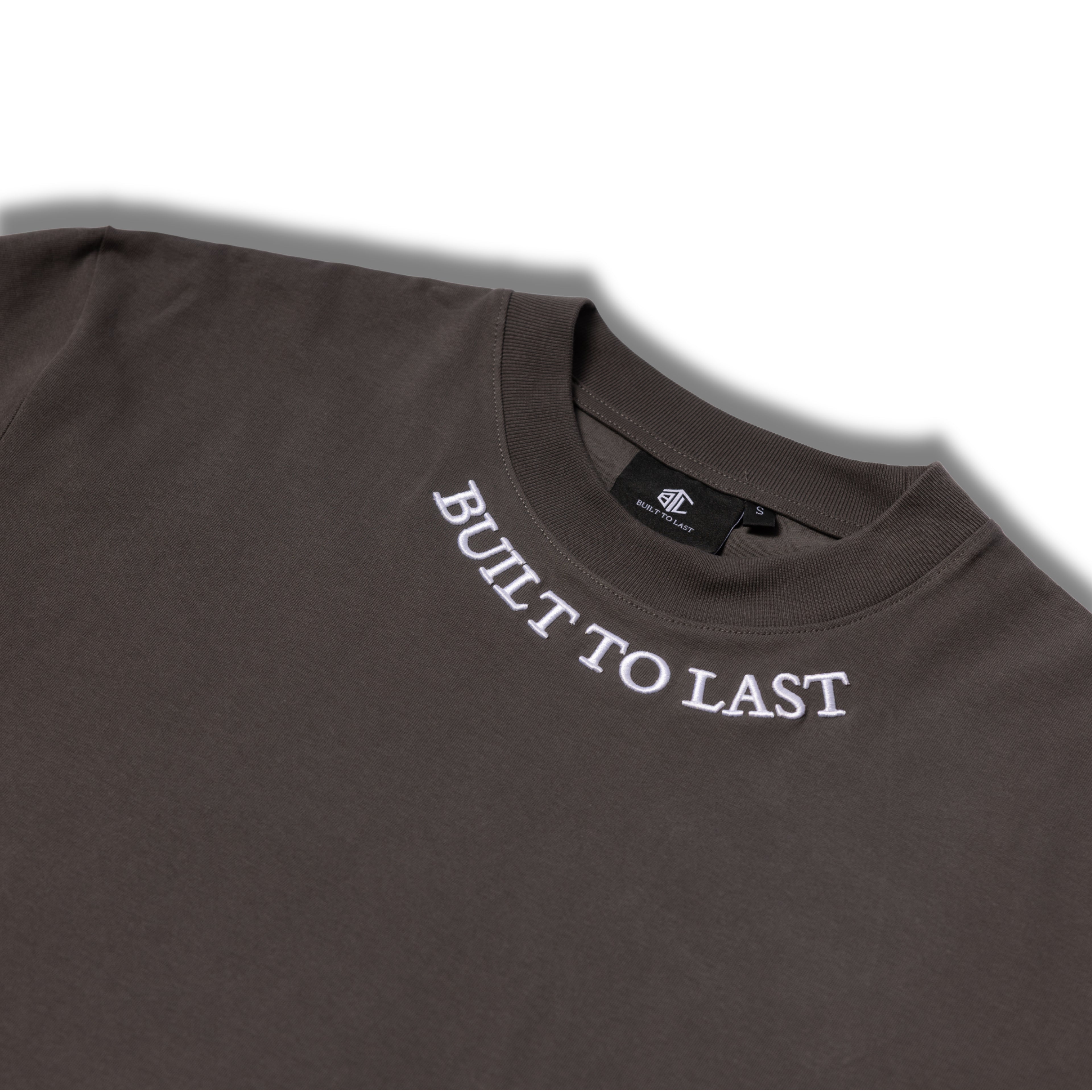 Close-up of Built to Last Legacy Tee Stone embroidered neckline logo on premium heavyweight cotton T-shirt