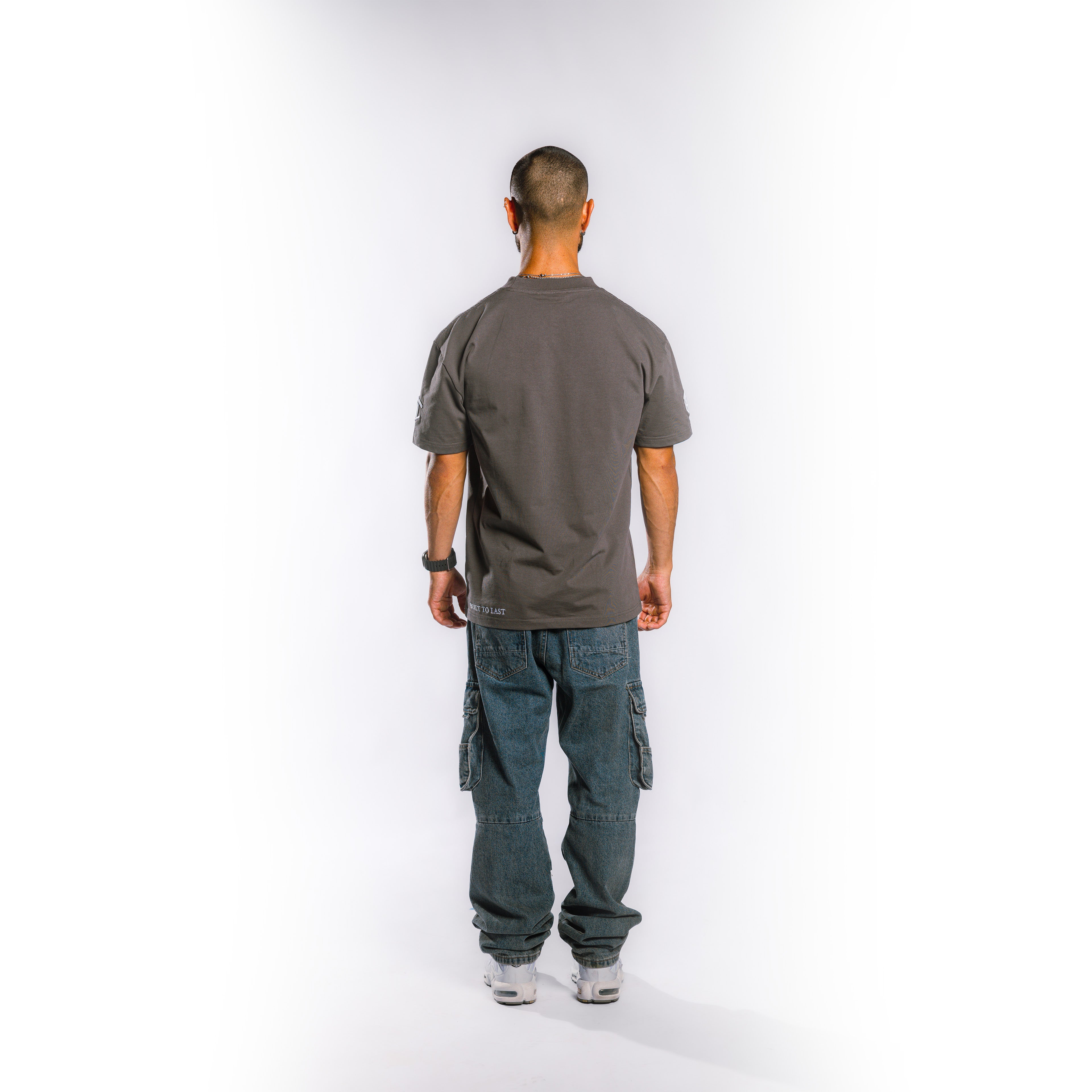Back view of model wearing Built to Last Legacy Tee Stone heavyweight cotton T-shirt with minimalist streetwear design