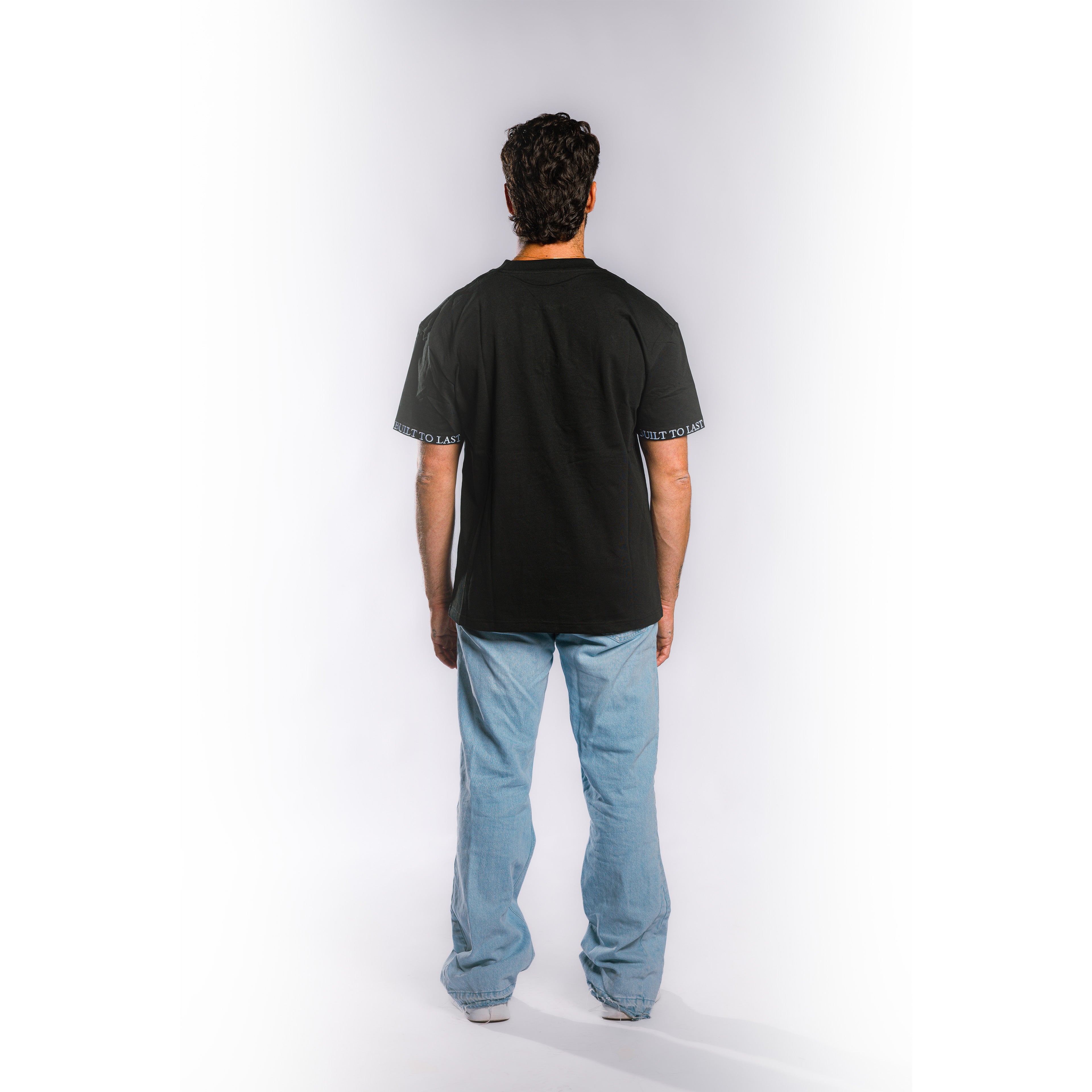 Back view of model wearing Built to Last Monolith Tee Black heavyweight cotton T-shirt with branded sleeve detail
