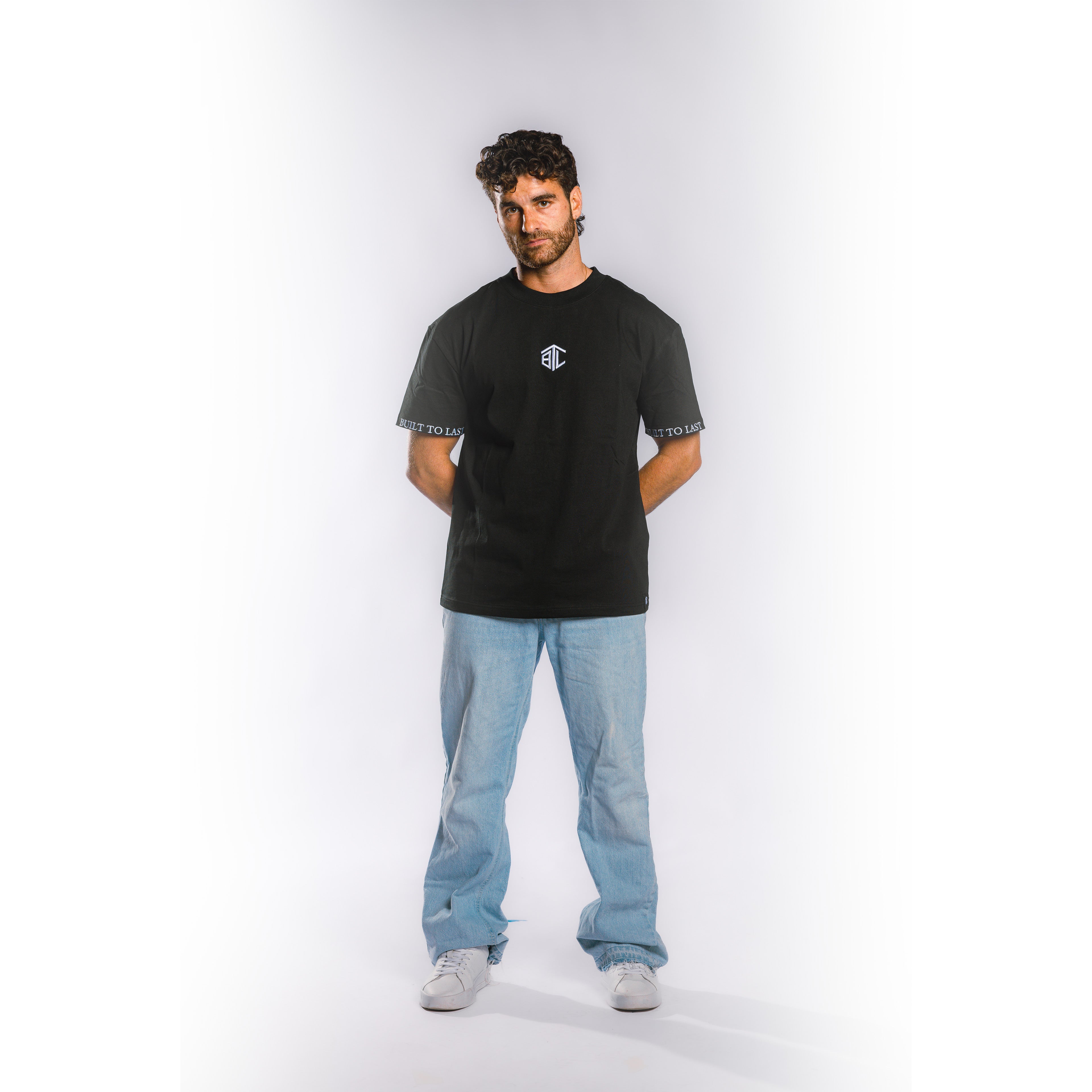Front view of model wearing Built to Last Monolith Tee Black heavyweight cotton T-shirt with embroidered chest logo and branded sleeve detail