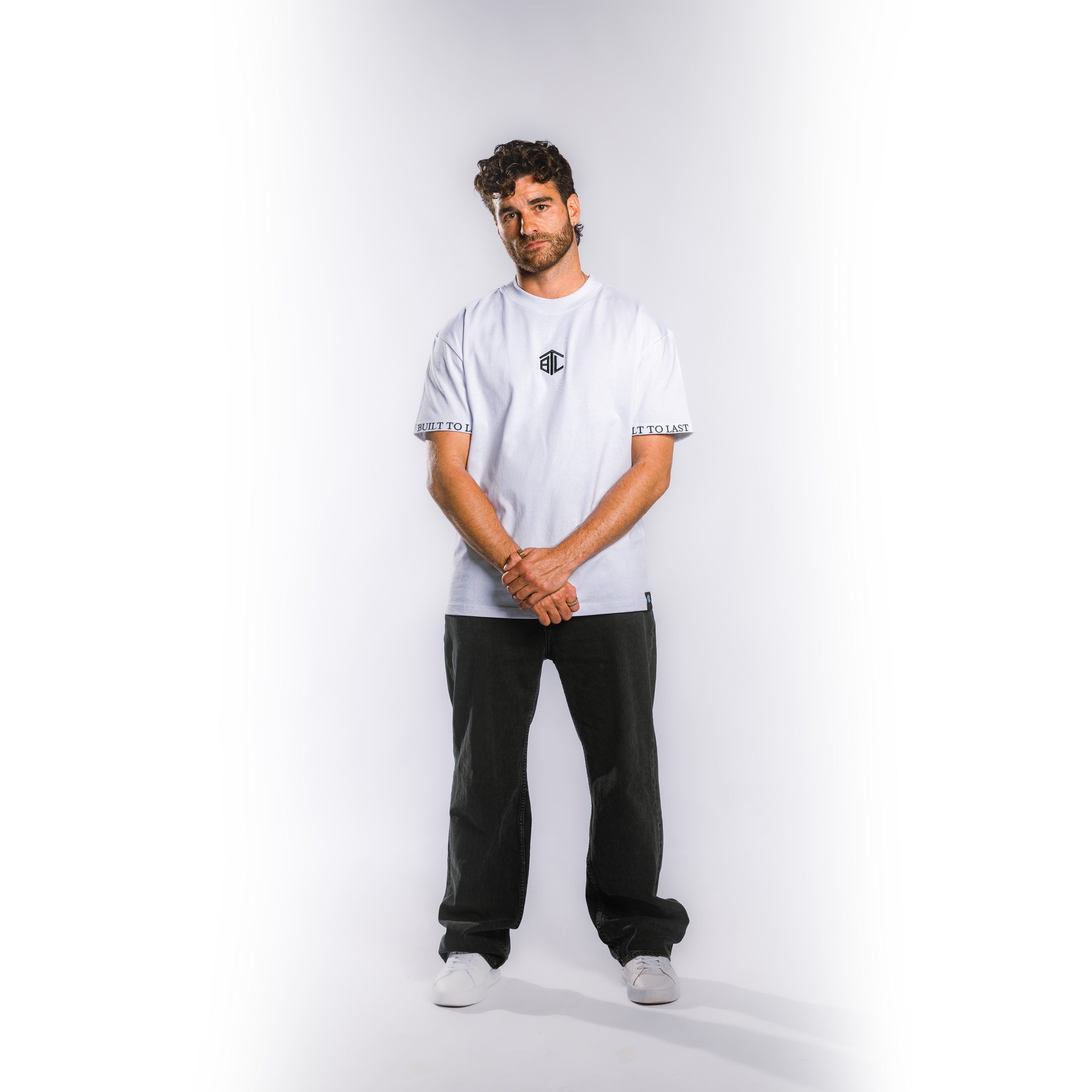 Front view of model wearing Built to Last Monolith Tee White heavyweight cotton T-shirt with embroidered chest logo and branded sleeve detail